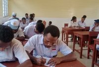 Anak-anak dan orang tua berdiskusi di rumah sambil melihat brosur sekolah baru untuk tahun ajaran mendatang.