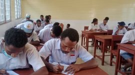 Anak-anak dan orang tua berdiskusi di rumah sambil melihat brosur sekolah baru untuk tahun ajaran mendatang.