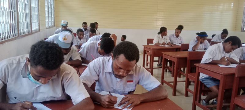 Anak-anak dan orang tua berdiskusi di rumah sambil melihat brosur sekolah baru untuk tahun ajaran mendatang.