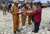 Bupati Deiyai Melkianus Mote menyerahkan Bendera Merah Putih kepada perwakilan OPD dalam apel gabungan peringatan HUT RI ke-80 di halaman Kantor Bupati Deiyai, 31 Juli 2025.
