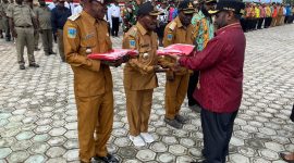 Bupati Deiyai Melkianus Mote menyerahkan Bendera Merah Putih kepada perwakilan OPD dalam apel gabungan peringatan HUT RI ke-80 di halaman Kantor Bupati Deiyai, 31 Juli 2025.