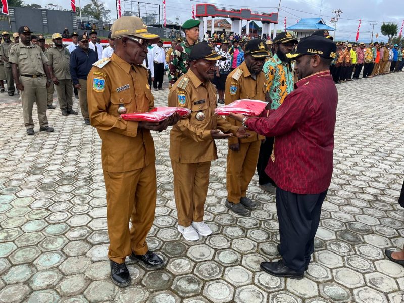 Bupati Deiyai Melkianus Mote menyerahkan Bendera Merah Putih kepada perwakilan OPD dalam apel gabungan peringatan HUT RI ke-80 di halaman Kantor Bupati Deiyai, 31 Juli 2025.