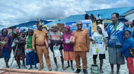 Bupati Deiyai, Melkianus Mote, (kiri) menyerahkan bahan bangunan secara simbolis kepada salah seorang janda/duda di Halaman Kantor Bupati Deiyai, Selasa (18/11).