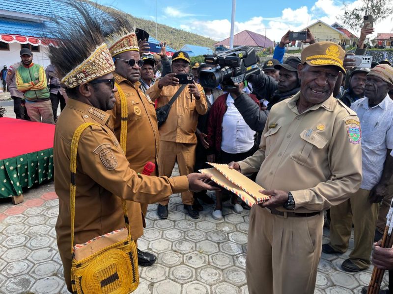 Bupati Deiyai, Melkianus Mote, menyerahkan penghargaan kepada Ketua Tim Pemekaran Kabupaten Deiyai, Mesak Pakage (kanan), yang dikenal sebagai 